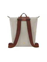 Mochila Longchamp de la línea Le Pliage Original, tamaño M, en color rosado con solapa y asas de cuero marrón.