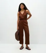 Pantalón tipo pantacourt de tiro alto, confeccionado en liocel color marrón. Presenta cierre frontal con botones forrados y elástico en la parte posterior de la cintura.