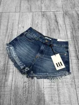 Short de jean tiro bajo color azul con lavado medio, roturas en los bordes y detalles deshilachados en el ruedo.