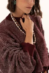 Buzo de punto color vino con diseño de trama geométrica, cuello redondo, mangas largas con puños ajustables mediante cordones y terminaciones acanaladas.