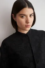 Chaqueta bomber de corte recto en tejido jacquard con estampado floral en tono sobre tono negro, cuello mao y cierre frontal de broches a presión.