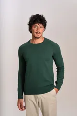 Sweater de punto fino color verde oscuro, con cuello redondo y mangas largas con puños acanalados. Presenta un pequeño logo bordado en el pecho.