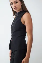 Chaleco negro de cuello alto con cierre frontal de cremallera plateada, corte entallado y confeccionado en tejido crepé.
