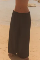 Pantalón negro de tiro medio, estilo culotte, con cintura elástica fruncida y piernas muy anchas. Posee bolsillos laterales ocultos.