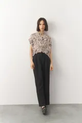 Blusa corta de manga corta con estampado en blanco y negro, cuello mao y cierre frontal con botones. Cuenta con detalle de elástico fruncido en la cintura que genera un efecto peplum.