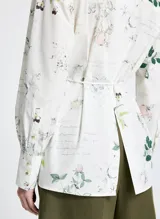 Camisa de manga larga con estampado floral y de texto, con cuello clásico, cierre frontal con botones y lazo ajustable en la cintura.