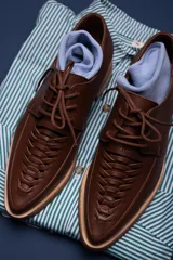 Zapato acordonado color marrón, con suela plana y cordones finos.