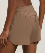 Short deportivo femenino color marrón topo, estilo runner, con cintura elástica y aberturas redondeadas en los laterales.