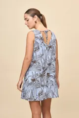 Vestido corto sin mangas de color celeste con estampado botánico en tonos marrones, de silueta amplia, escote redondo y volado en el ruedo.