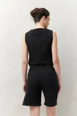 Bermuda negra de tiro medio con silueta recta y largo a la altura de la rodilla. Presenta bolsillos laterales y traseros, y costuras visibles.