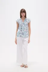 Blusa de rayón con estampado floral en tonos azules y celestes sobre fondo blanco. Presenta cuello en V, botones frontales y mangas cortas con frunces en los hombros.