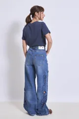 Pantalón de jean azul con bordados florales y aberturas en forma de flor en las piernas.
