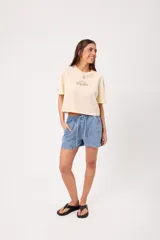 Remera coral cropped, de manga corta, con estampa trasera colorida de un perro surfeando y el texto "Rusty County Surf Club".
