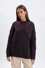 Sweater de punto con diseño de trenzas verticales, cuello redondo y mangas largas. Presenta un corte holgado y terminaciones acanaladas en cuello, puños y ruedo.