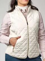 Chaleco sin mangas capitoneado en color beige, con cierre frontal y bolsillos laterales. Presenta un diseño entallado con cuello alto.