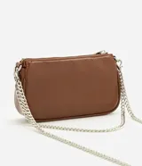 Cartera tipo baguette pequeña Satinato, confeccionada en PU color marfil, de formato alargado y estructura maleable. Cuenta con cierre superior de cremallera, placa frontal aplicada con el logo de la marca y asa de cadena doble metálica en tono plateado que permite llevarla al hombro o cruzada.