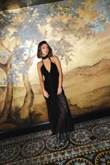 Vestido largo negro de encaje con escote profundo halter, espalda abierta, detalles fruncidos al cuerpo y falda larga semitransparente con tiras largas para atar.