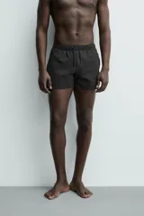 Short de baño negro de tejido técnico con estructura ripstop resistente a desgarros, cintura ajustable con cordón y bolsillos laterales.