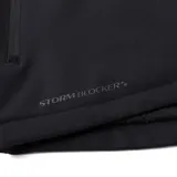 Chaqueta técnica negra de Caterpillar, diseñada con tecnología Storm Blocker+ para protección contra agua y viento. Cuenta con capucha ajustable y extraíble, cierre frontal completo con protector de barbilla, bolsillo en el pecho y bolsillos laterales con cremalleras impermeables, y logo de la marca en el brazo.