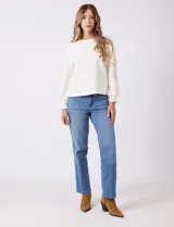 Buzo blanco de modal, corte clásico, con mangas largas abullonadas y apliques de crochet floral en los hombros y parte superior de las mangas.