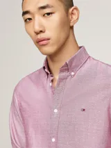 Camisa de corte slim confeccionada en algodón Oxford con textura dobby. Presenta cuello con botones, puños redondeados y el logo de Tommy Hilfiger bordado en el pecho.