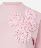 Remera blanca de algodón con cuello redondo y corte boxy, con apliques de flores de tejido en relieve en la zona del pecho.