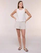 Blusa sin mangas de lino color beige, de silueta recta y relajada, con escote redondo y cartera de botones frontales.