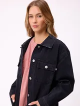 Campera de jean de corte oversize, color azul lavado, con cierre frontal de botones metálicos, bolsillos frontales con solapa en el pecho y bolsillos laterales inferiores.