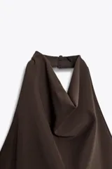 Vestido largo color marrón oscuro, con cuello halter que forma un drapeado en el busto. La parte superior es ajustada y la falda es larga con un panel inferior fruncido y drapeado en tela más liviana.