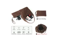 Bolso tipo hobo de gamuza color marrón, con diseño decorado con múltiples ojales metálicos dorados. Incluye una pequeña cartera tipo sobre a juego con correa de muñeca.