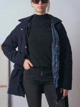 Campera de pana color marrón, con diseño acolchado, cuello camisero, cierre frontal oculto y cinturón ajustable con hebilla a tono. Presenta bolsillos frontales con solapa y mangas largas de corte holgado.