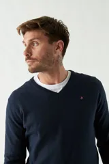 Sweater de punto color rosa con cuello en V y logo bordado en el pecho.