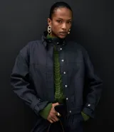 Campera bomber de denim azul oscuro, con cuello alto, cierre frontal con botones a presión ocultos, mangas largas con puños ajustables y diseño de largo corto.