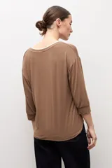 Remera color marrón topo de manga tres cuartos, con escote en V y detalle de ribete blanco en el cuello.
