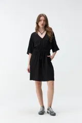 Vestido corto beige con escote en V, mangas cortas amplias y cintura elastizada con lazo ajustable.