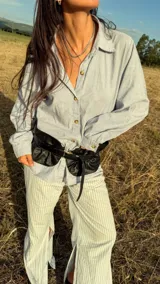 Cinturón ancho tipo corset confeccionado en cuero genuino, con diseño fruncido y cierre frontal mediante hebilla metálica.