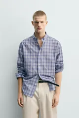 Camisa de corte relajado confeccionada en tejido de algodón, con estampado de cuadros en tonos azules. Presenta cuello abotonado, manga larga con puños abotonados y cierre frontal con botones.