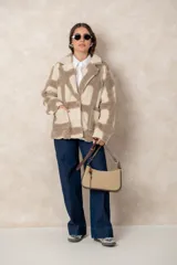 Chaqueta oversize de textura afelpada con diseño de cuadros en tonos beige y marrón. Presenta solapas clásicas, cierre frontal con un botón joya y bolsillos laterales amplios.