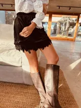 Minifalda negra de terciopelo con cintura elástica y ruedo con plumas.