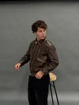 Campera estilo bomber de cuero sintético en color marrón con efecto desgastado. Presenta cuello camisero, cierre frontal con botones metálicos, bolsillos frontales con solapa y cintura elástica.