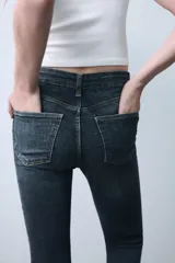 Jeans skinny de tiro alto en color negro, confeccionados en tejido super elástico de cinco bolsillos, con cierre frontal de cremallera y botón metálico.