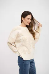 Buzo de tejido de punto con diseño floral en tonos crema y beige, de corte holgado, cuello redondo y mangas largas con puños acanalados.