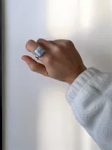 Anillo de acero quirúrgico con piedra cuadrada de diseño marmolado en tonos blancos y grises.
