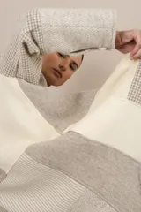 Camisa larga de lana fina sin teñir, con cuello mao y cierre frontal con un botón. Presenta un diseño de patchwork en tonos beige y gris con patrones de pata de gallo y texturas lineales. Las mangas son largas con tajo y detalle de botón en los puños.