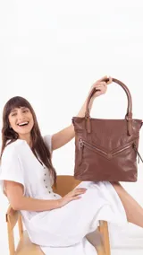 Cartera tipo shopper de tamaño grande, confeccionada en símil cuero con textura efecto croco. Presenta dos bolsillos frontales con cierre metálico en disposición angular, cierre superior principal, bolsillo trasero con cierre, doble asa corta para llevar al hombro y correa larga desmontable y regulable.
