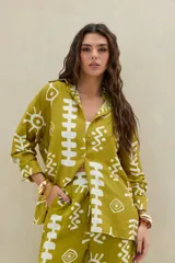 Camisa verde militar de manga larga con estampado abstracto en color blanco, de corte holgado y cierre frontal con botones.