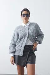 Short tipo skort de cuero sintético color negro, con diseño envolvente frontal que simula una pollera, tiro medio y acabado liso.
