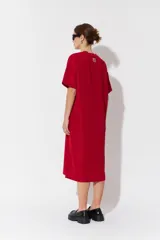 Vestido largo de manga corta y corte oversize, confeccionado en tejido con textura. Presenta cuello redondo y un parche decorativo en la parte posterior.