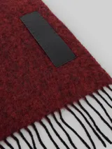 Bufanda rectangular color rojo oscuro con textura y flecos en los extremos.