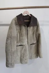 Campera reversible de cuero genuino napalán color marrón oscuro, con cuello, solapas, bolsillos frontales y detalles en corderito negro. Cierre frontal con cremallera.